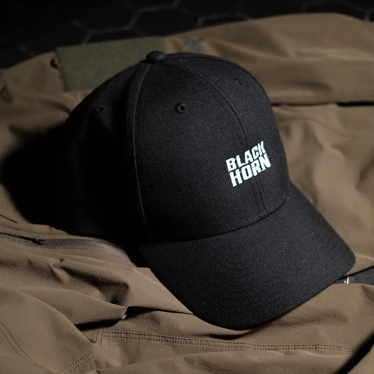 Close-up lifestyle image of the Blackhorn MVP Hat resting on a tan jacket, showcasing the structured crown and raised embroidered logo.