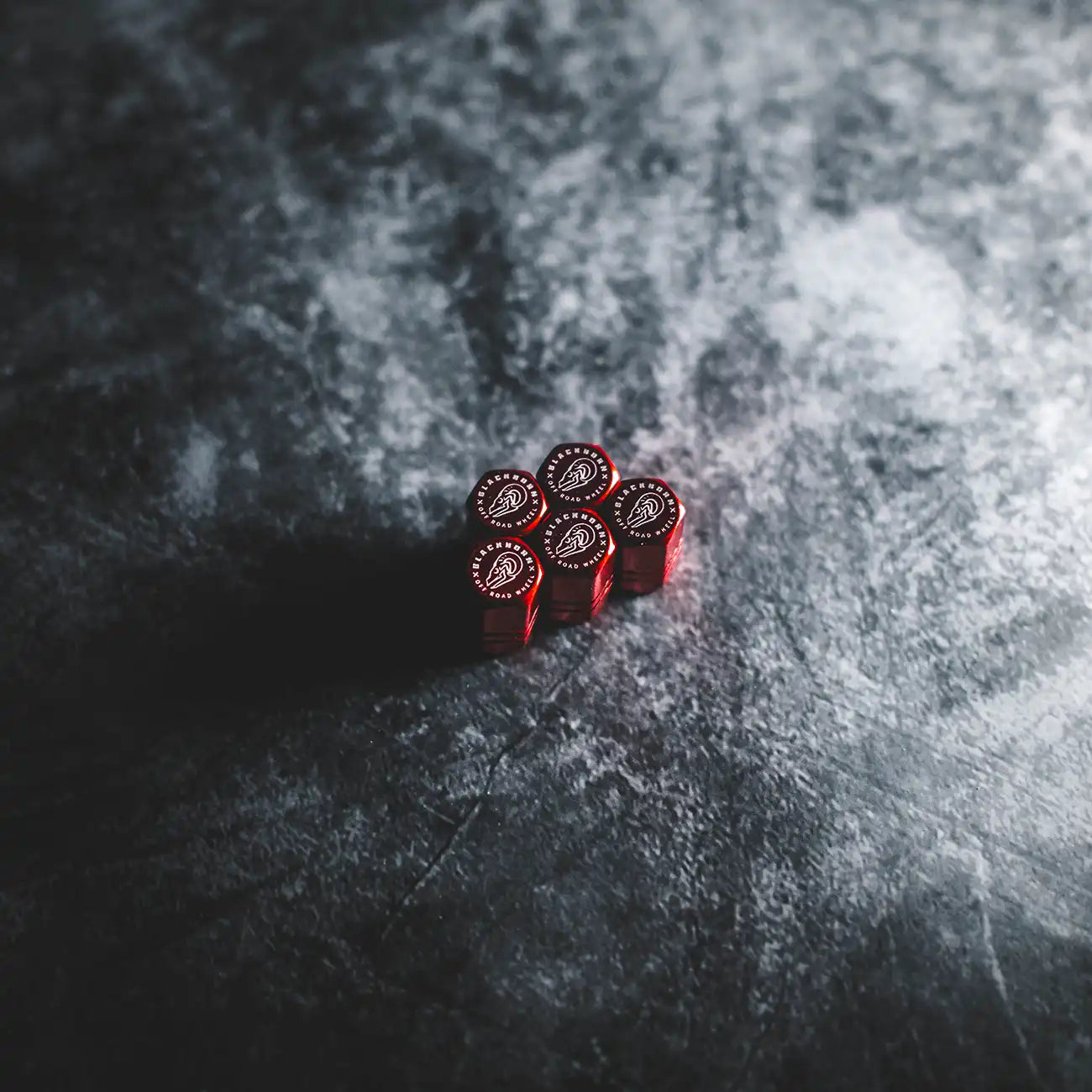 Red Blackhorn valve stem caps arranged on dark textured surface with crest logo visible.