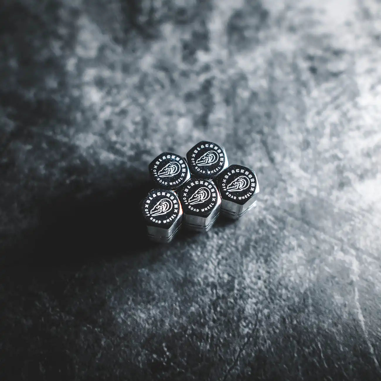 Silver Blackhorn valve stem caps arranged on dark textured surface with crest logo visible.